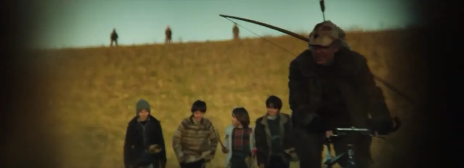 Village boys walking home across a field with the silhouettes of medieval archers on the hilltop behind them